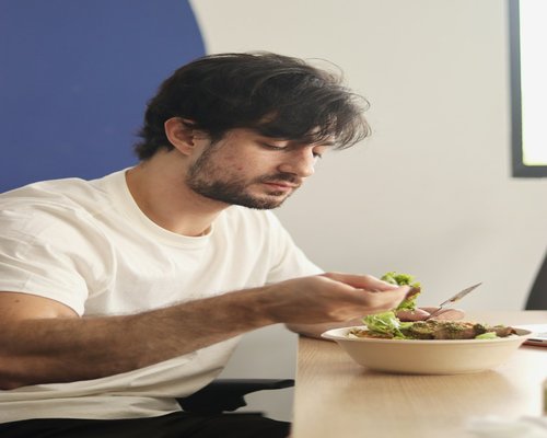Man eating a packed lunch at his desk in an office environment